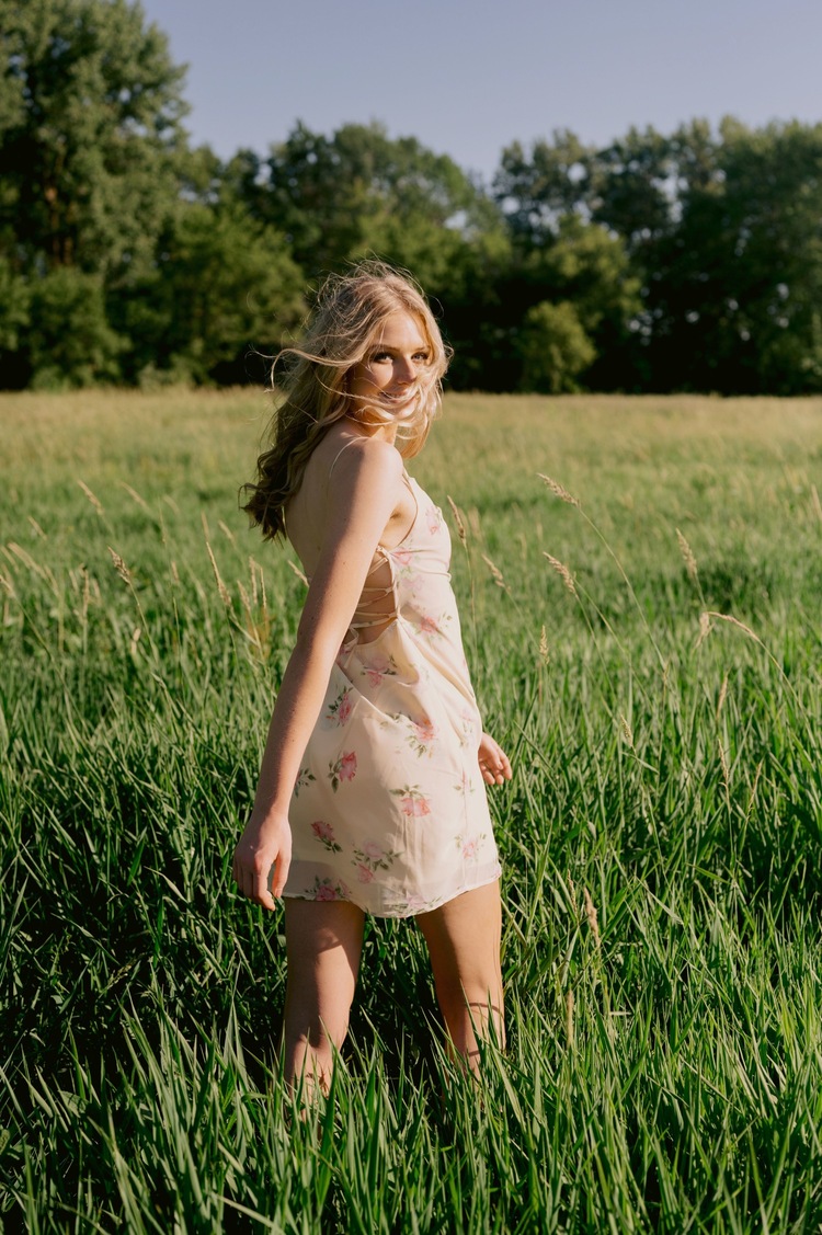 Lovely lady wearing dainty dress smiling at the camera as she stands in the middle of a field, captured by Mary Shelton Media